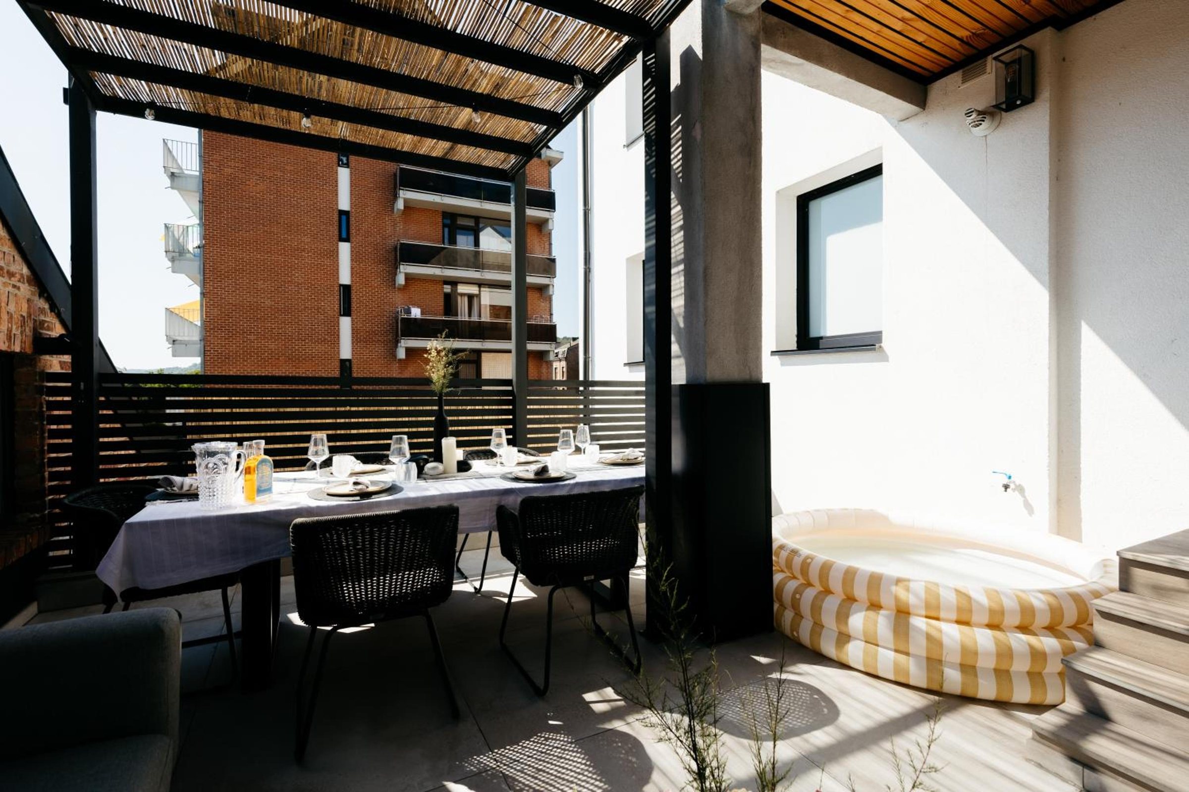 Grande terrasse couverte avec salon et table extérieure – The Edgewater Suites ParkView, Namur