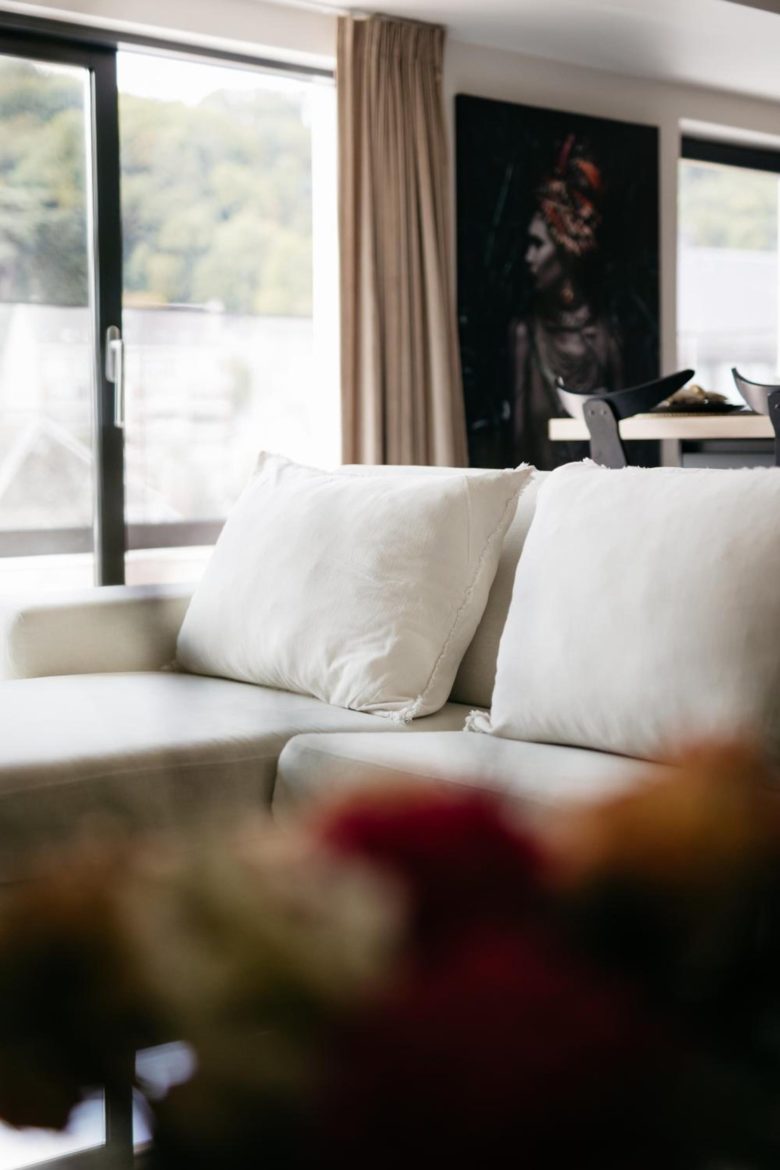 Salon lumineux avec canapé blanc – The Edgewater Suites Riverside, Namur